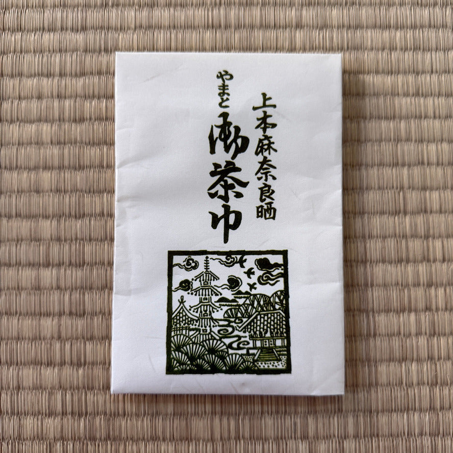 White napkin with black text and design on a woven mat background