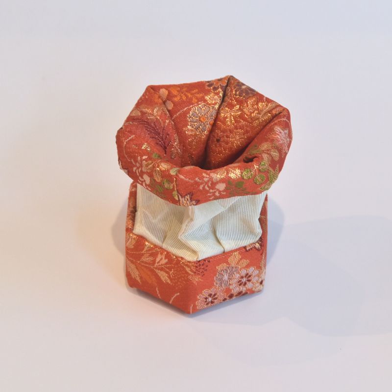 Decorative red fabric box with floral patterns on a white background