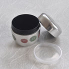 Tea container with black, silver, and clear lids on a textured white surface.