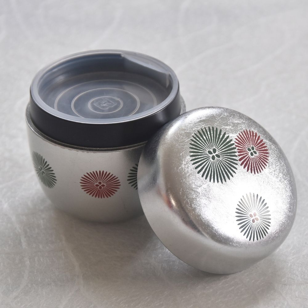 Silver container with decorative lid on a light gray background