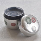 Silver container with decorative lid on a light gray background