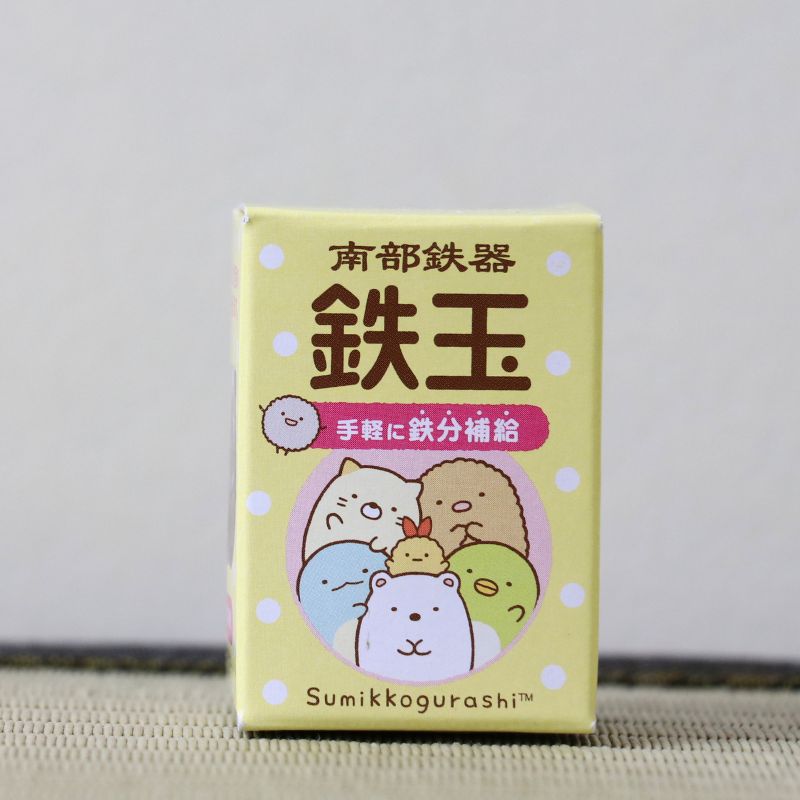 A yellow Sumikkogurashi box with Japanese text and illustrations of the character group, photographed against a plain light background.