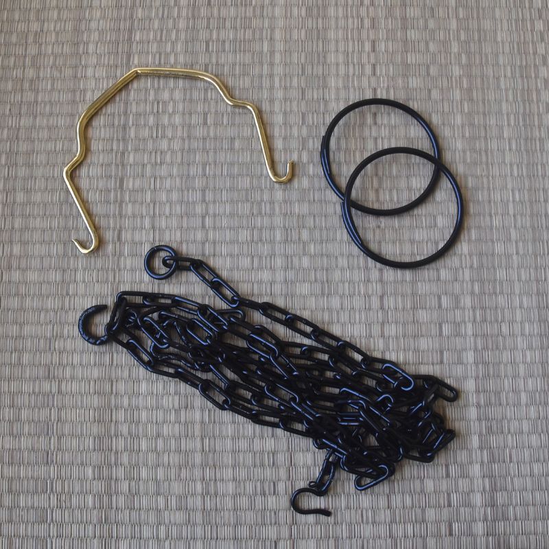 Set of black chains, gold hook, and black rubber bands on a textured gray surface