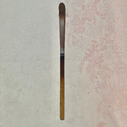 Long, thin metallic object on a textured surface
