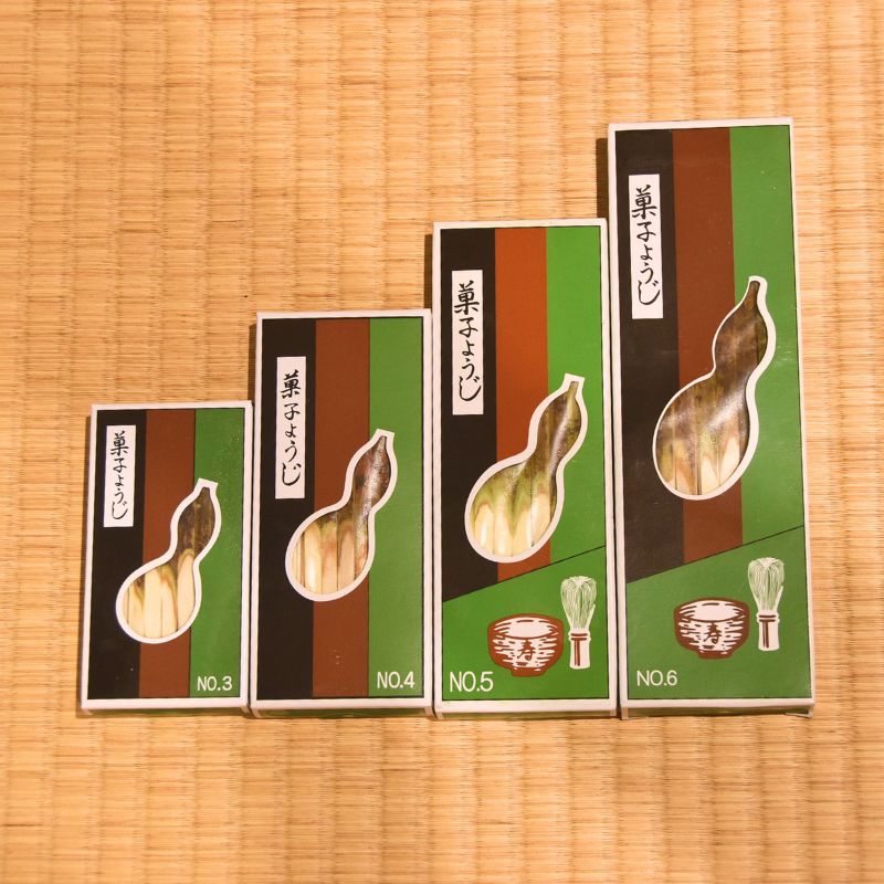 Four small boxes with green and brown design on a woven mat background