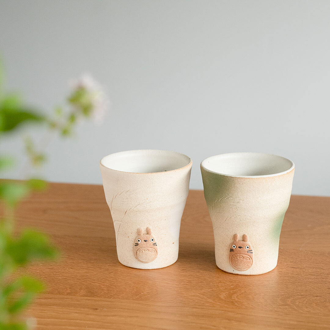 Two ceramic cups with animal designs on a wooden surface