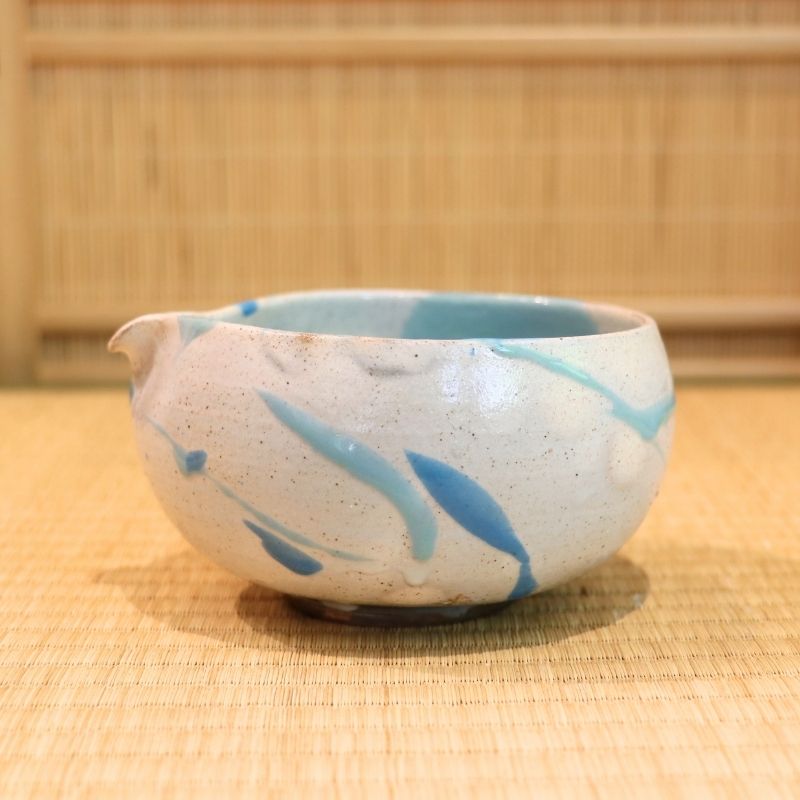 Ceramic bowl with blue accents on a woven mat