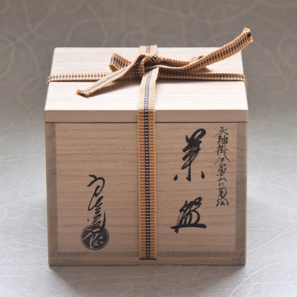 Wooden gift box with a ribbon and Japanese text on a neutral background