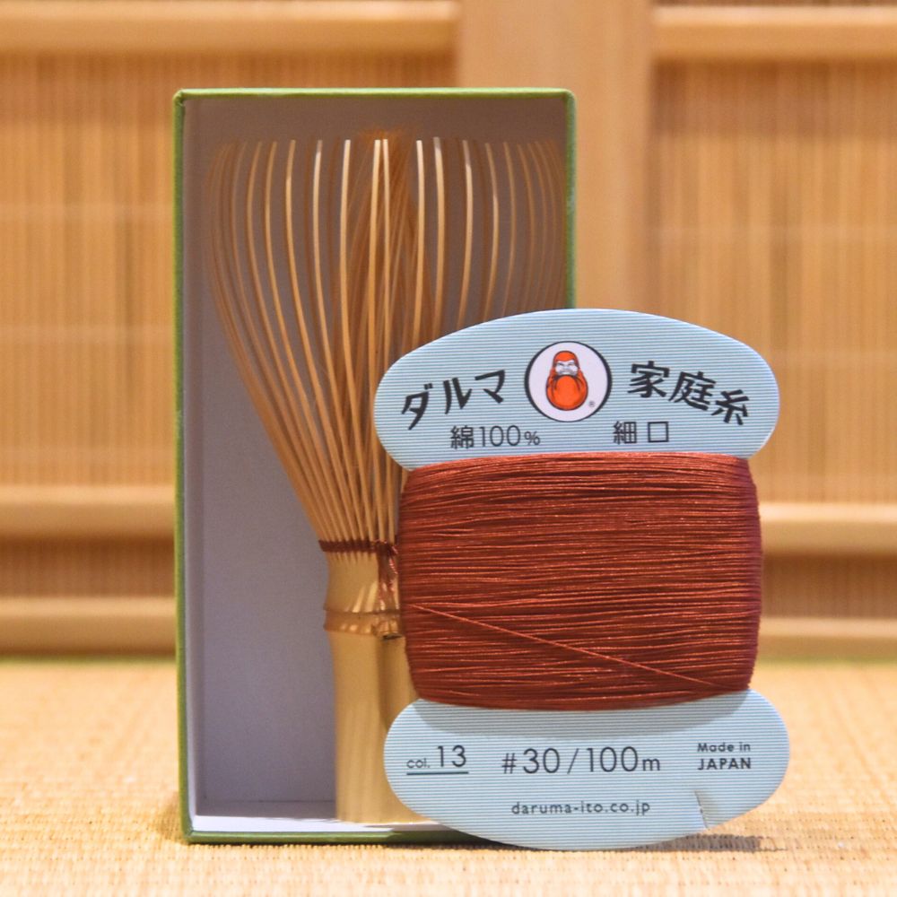 Ball of brown thread with a wooden tool in a box on a wooden background