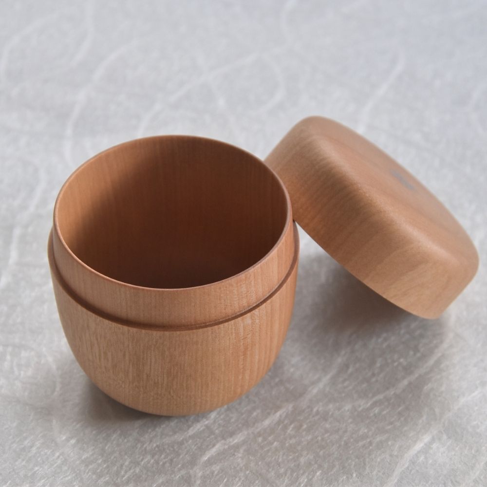 Wooden container with lid on a textured white background