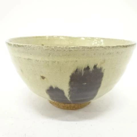 Back view of the pre-owned matcha bowl showing its restrained cream and muted green glaze, rounded form, and exposed clay foot.