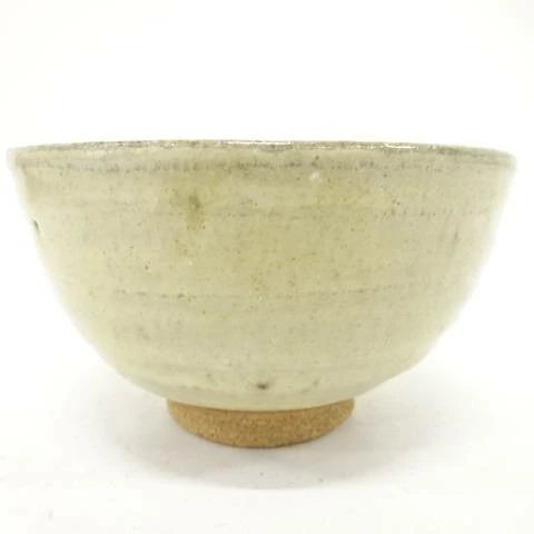 Back view of the pre-owned matcha bowl showing its restrained cream and muted green glaze, rounded form, and exposed clay foot.