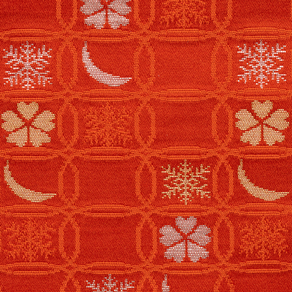 Close-up of red Nishijin silk brocade with overlapping shippo circles, snow crystals, crescent moons, and flowers.