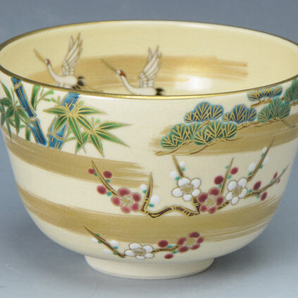 Angled view of the Kyo Ware matcha bowl showing cranes, pine, bamboo and plum decoration with gold leaf accents