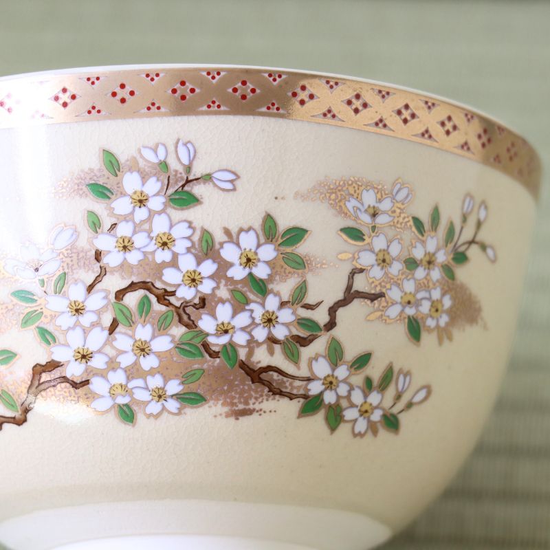 Close-up of the Eika Miyaji matcha bowl showing hand-painted cherry blossoms, green leaves, and intricate gold detailing