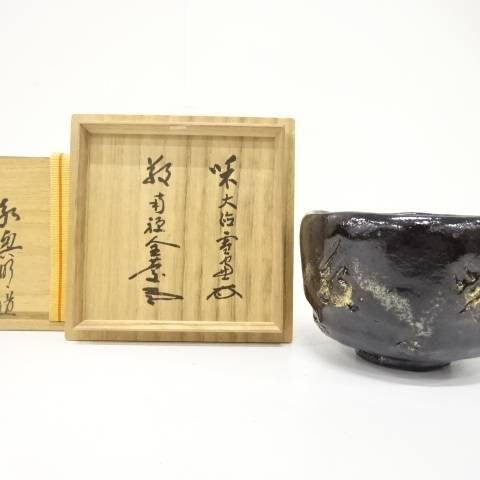 Pre-owned Eiko Meido Mandokoro Kiln matcha bowl with a midnight glaze and gold botanical accents displayed beside its inscribed wooden storage box.