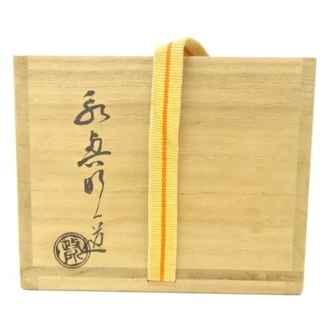 Exterior of the wooden storage box with Japanese calligraphy, a circular seal, and a yellow securing cord for the Eiko Meido Raku matcha bowl.