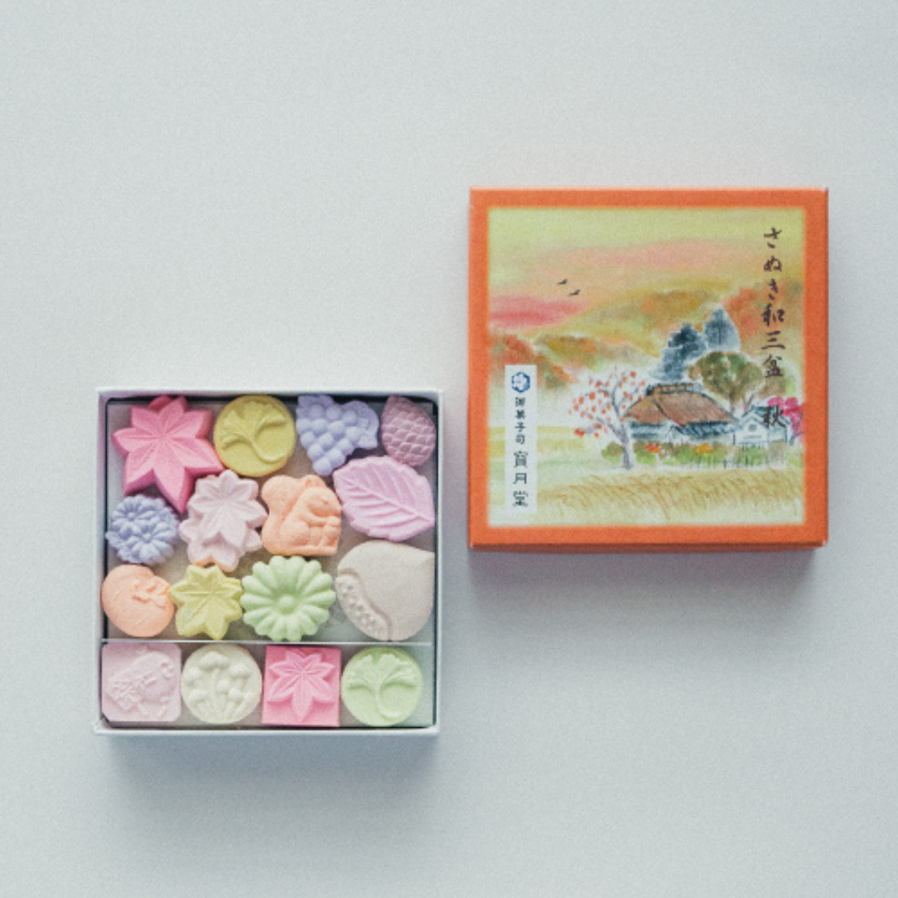 Box of colorful higashi with a decorative lid on a light gray background