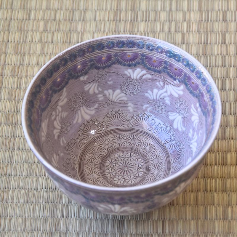 Decorative ceramic bowl with intricate patterns on a woven mat