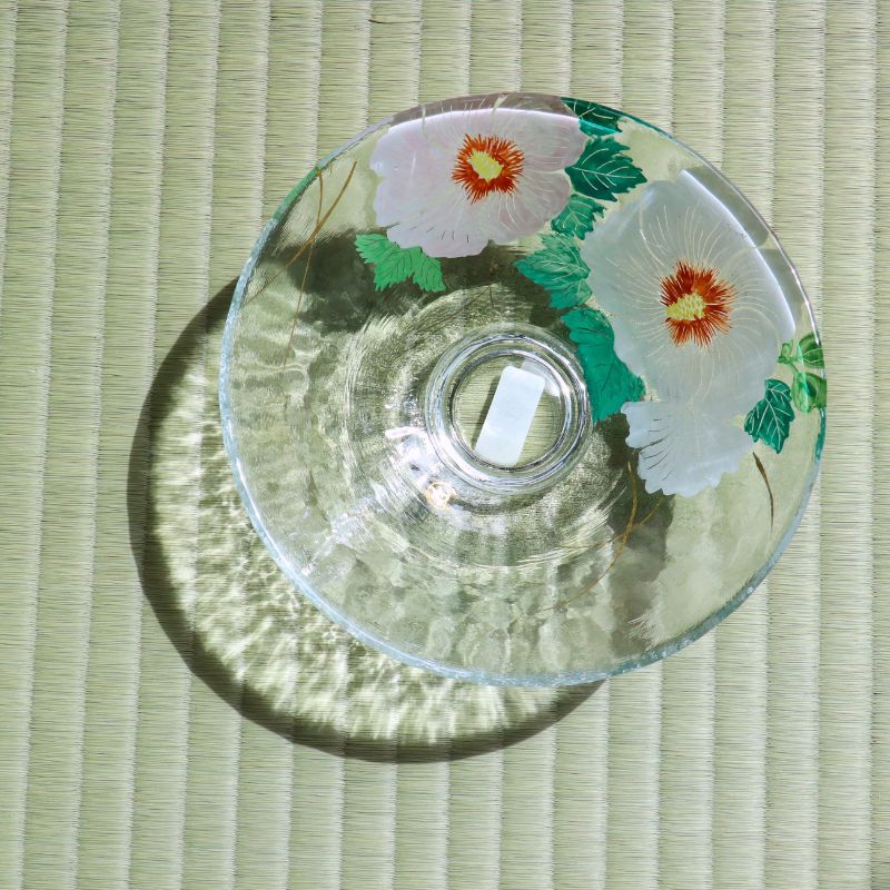 Overhead view of transparent glass matcha bowl with pink and orange Rose of Sharon flower decoration