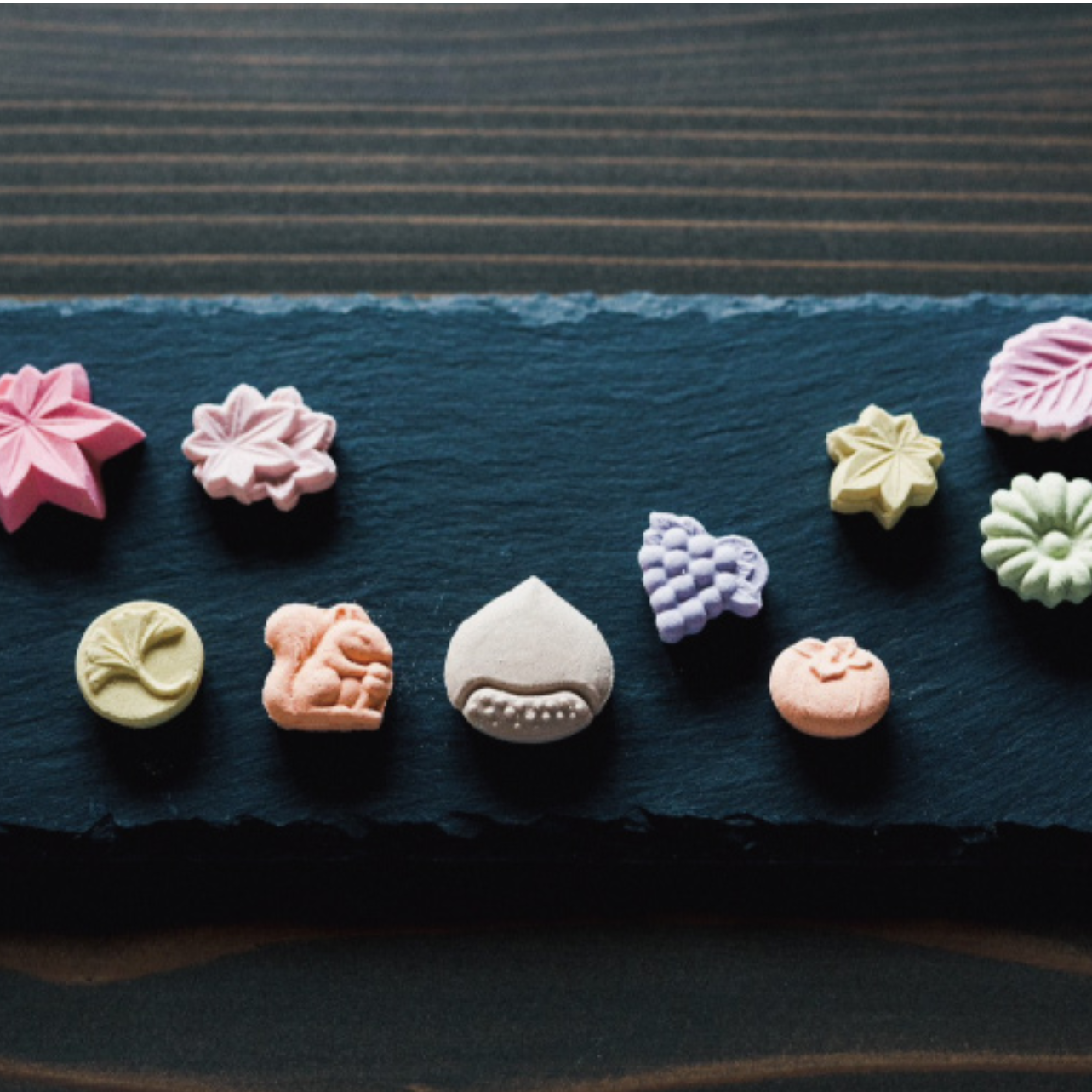Assorted colorful flower-shaped cookies on a dark surface
