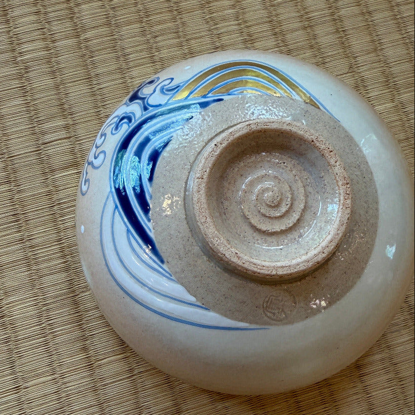 Underside view of the hand-painted matcha bowl showing its circular foot ring and cobalt-blue wave decoration around the lower exterior.