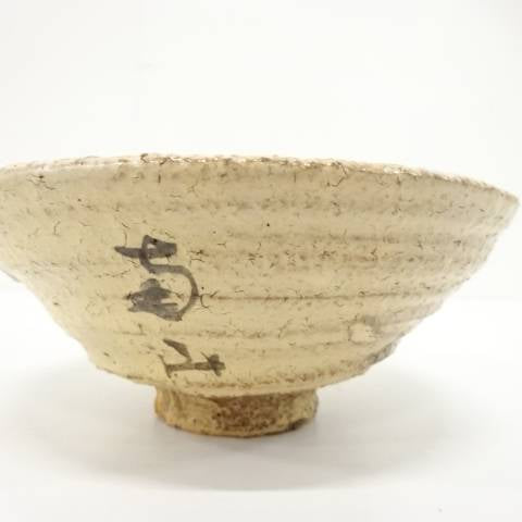 Back view of the Hagi Ware matcha bowl showing its softly irregular rim, earthy ivory glaze, and additional calligraphic brush mark.