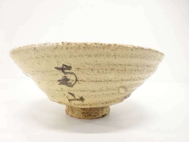 Back view of the Hagi Ware matcha bowl showing its softly irregular rim, earthy ivory glaze, and additional calligraphic brush mark.