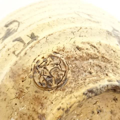 Close-up of the underside showing the textured Hagi clay, circular foot, firing variation, and impressed potter's mark.