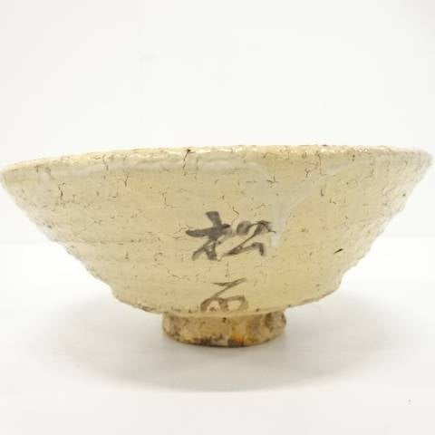 Right angled view of the pre-owned matcha bowl showing its gently flared form, horizontal surface texture, and dark painted accent near the foot.