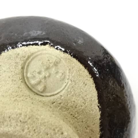 Close-up detail of the underside of the Kawasaki Waraku Black Raku matcha bowl showing the foot and impressed mark.