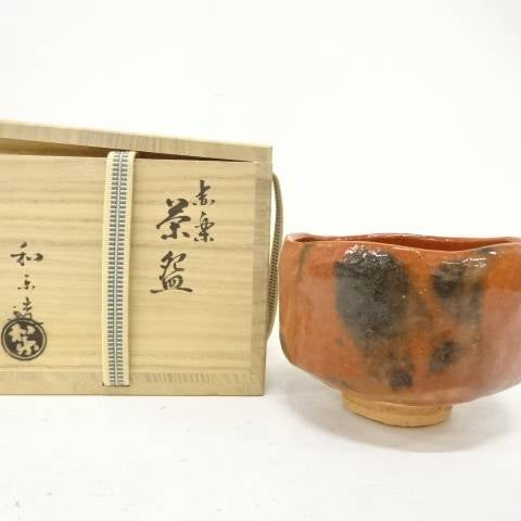 Pre-owned Kawasaki Waraku Red Raku matcha bowl displayed beside its inscribed wooden storage box.