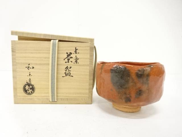 Pre-owned Kawasaki Waraku Red Raku matcha bowl displayed beside its inscribed wooden storage box.