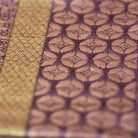 Close-up of textured fabric with a pattern, showing gold and purple colors.