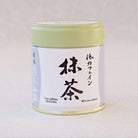 Cylindrical container of matcha tea with Japanese text on a light gray background