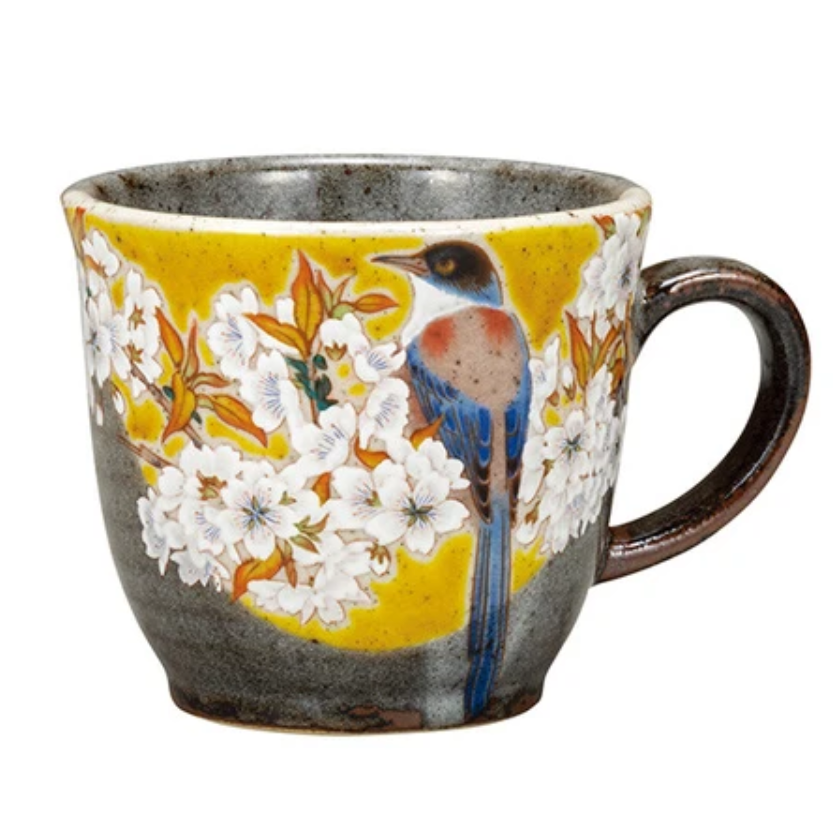 Ceramic mug with bird and floral design on a yellow background