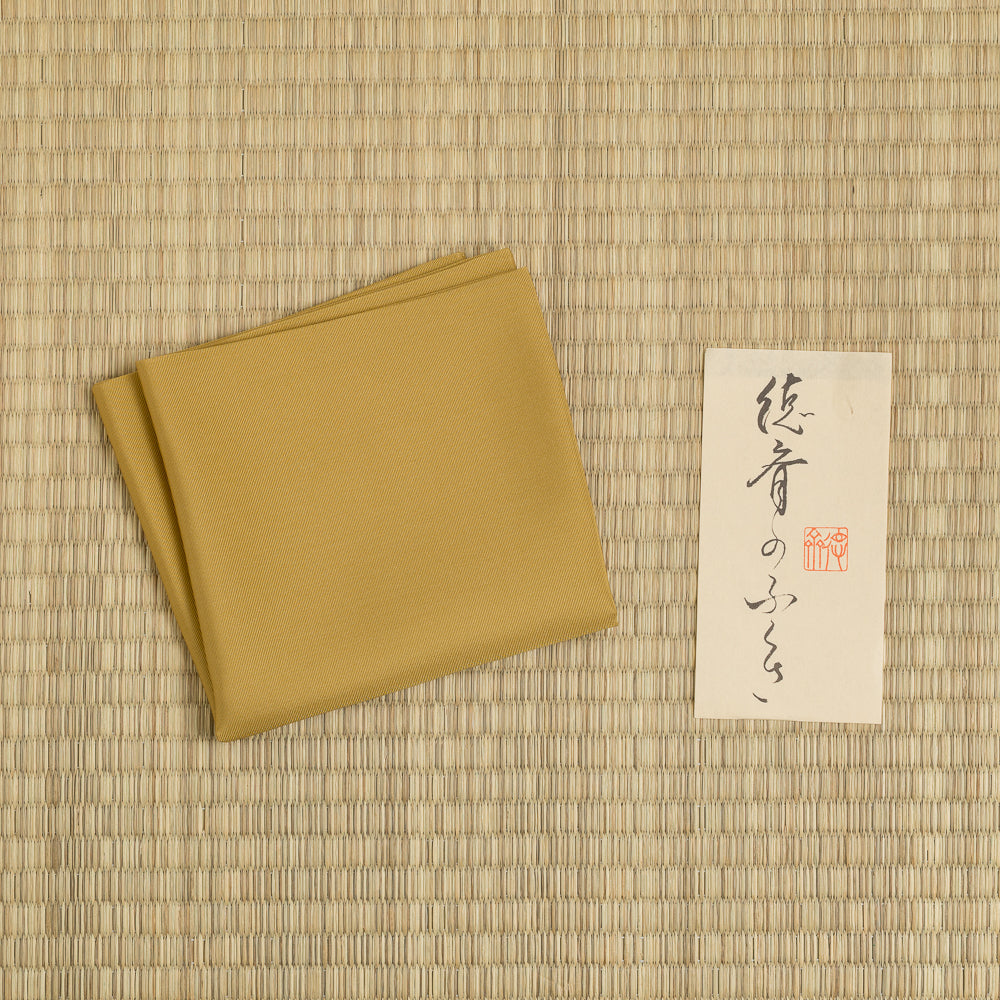 Kuwazome Mustard Yellow Silk Fukusa displayed on tatami, handcrafted in Kyoto for Japanese tea ceremony.