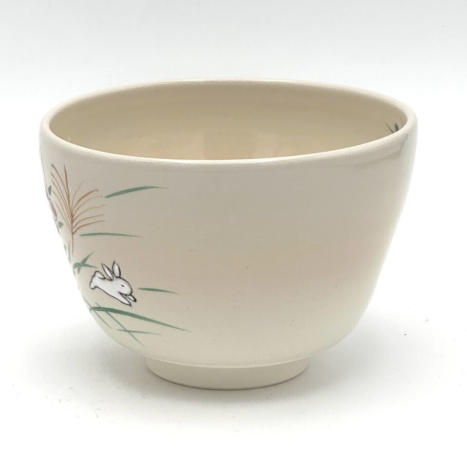 Angled view of the Kyo-yaki Akikusa ni Usagi chawan showing its rounded profile, ivory glaze, and partial hand-painted rabbit and autumn grass motif