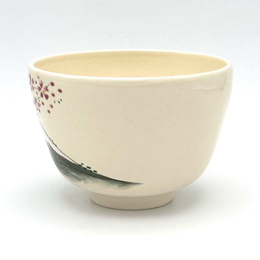 Angled view of the Kyo-yaki Mt. Fuji chawan highlighting its rounded shape, ivory glaze, pink blossoms, and hand-painted landscape detail