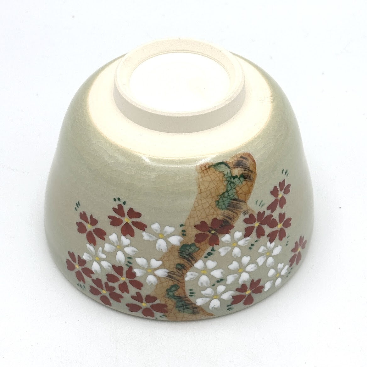 Underside view of the Kyo-yaki Sakurazume matcha bowl showing its ceramic foot and dense hand-painted cherry blossom decoration around the exterior