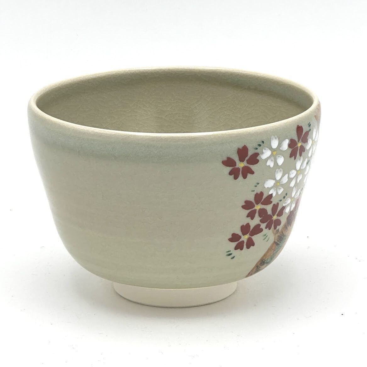 Side view of the hand-painted Kyo-yaki Sakurazume chawan showing clusters of pink and white cherry blossoms against the soft beige glaze