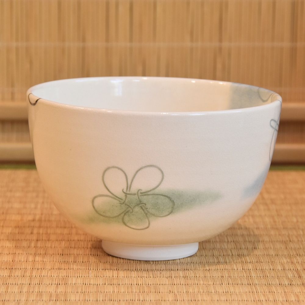 Side view of the Musubi Wakakusa matcha bowl showing a pale green knot motif and the softly rounded white form.