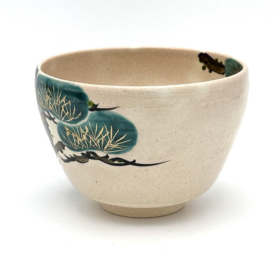 Angled view of the hand-painted Matsu Kyo Ware chawan showing layered green pine foliage and detailed branches
