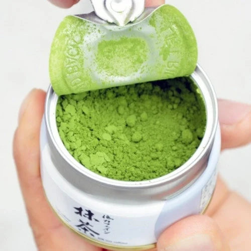 Container of green powder with a green lid, held by a hand on a white background