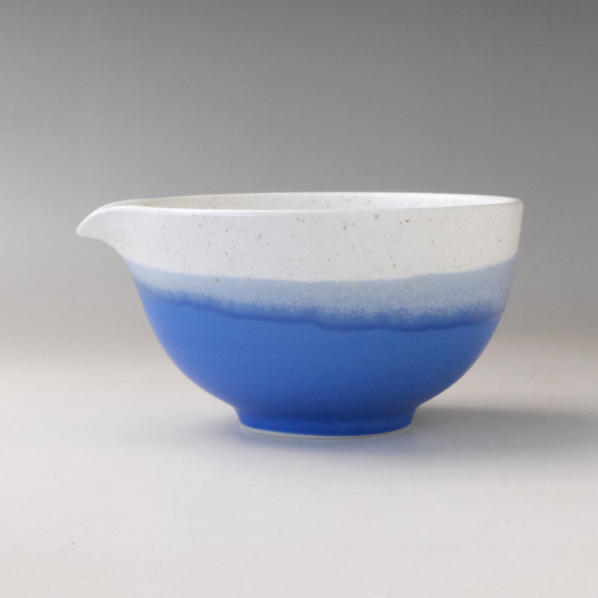 Left side profile of the Ocean Blue Mino Ware katakuchi matcha latte bowl showing its rounded form, pouring spout, and blue glazed exterior
