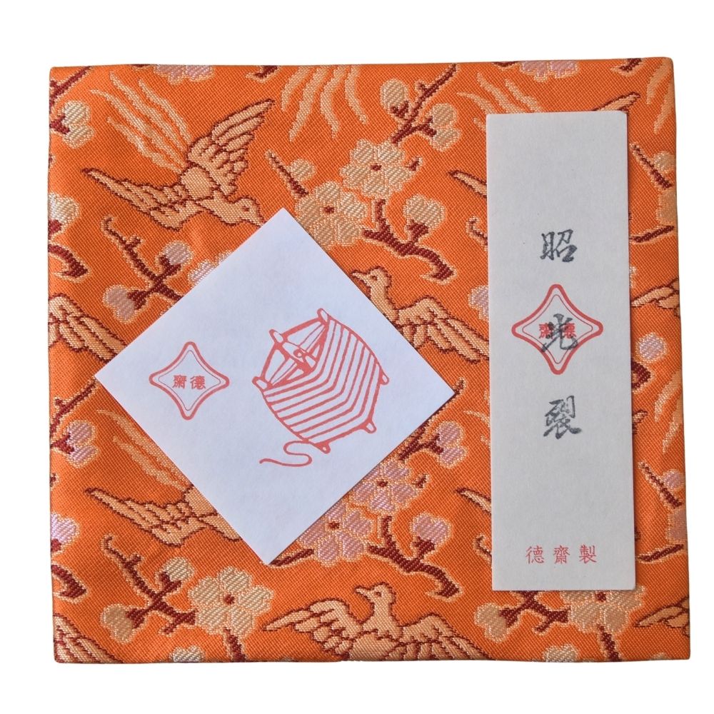 Decorative box with orange and gold pattern, featuring a white label and red design.