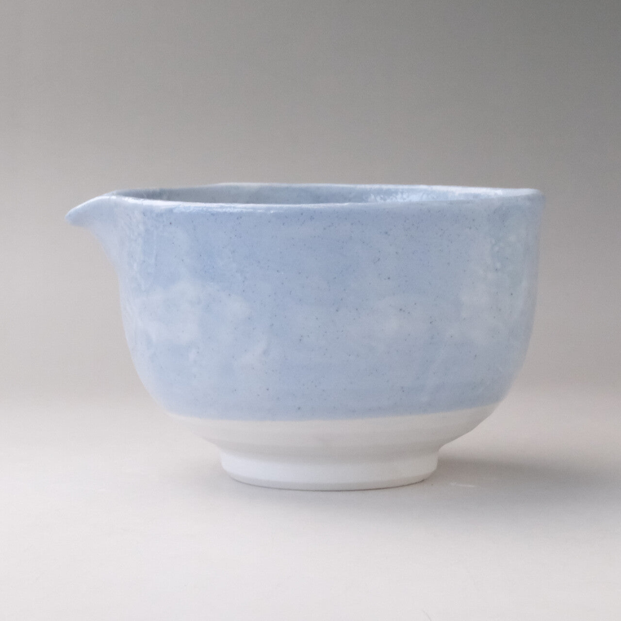 Side profile of the pale blue Mino Ware katakuchi matcha bowl showing its rounded shape, white foot, and soft cloudy finish.
