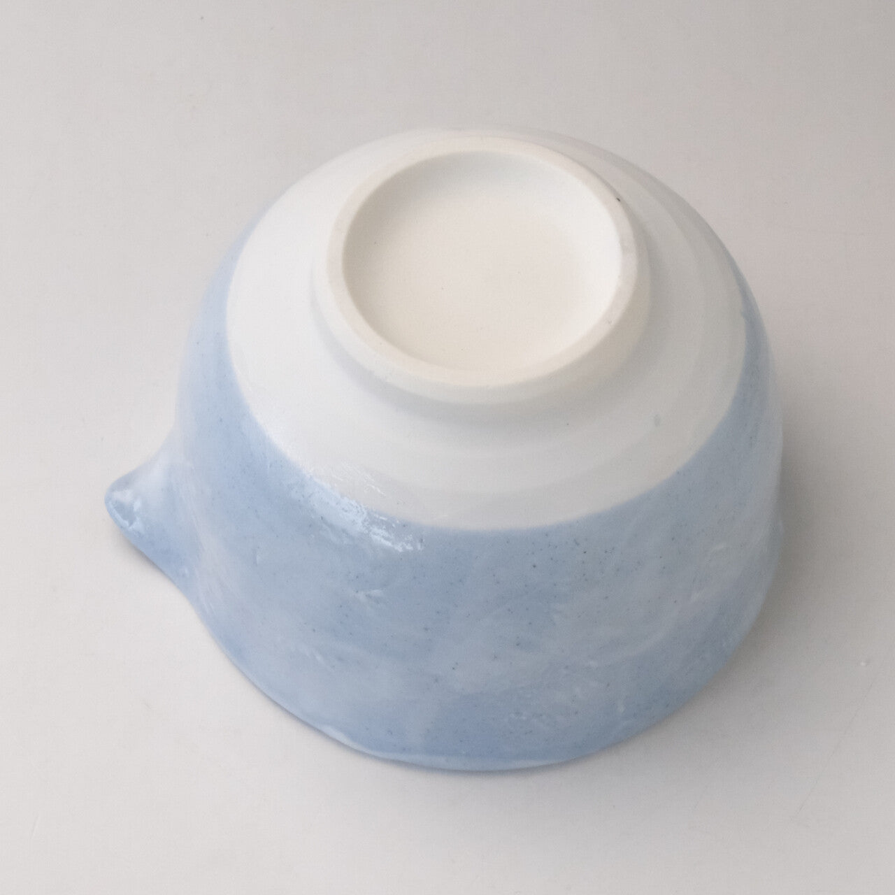 Underside view of the pale blue katakuchi matcha bowl showing the white foot ring and smooth glazed base.