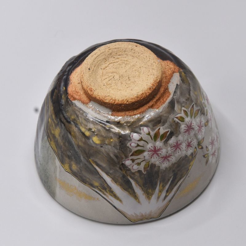 Angled underside view of the Mt. Fuji matcha bowl showing cherry blossom decoration, dark glaze, and the exposed clay foot.