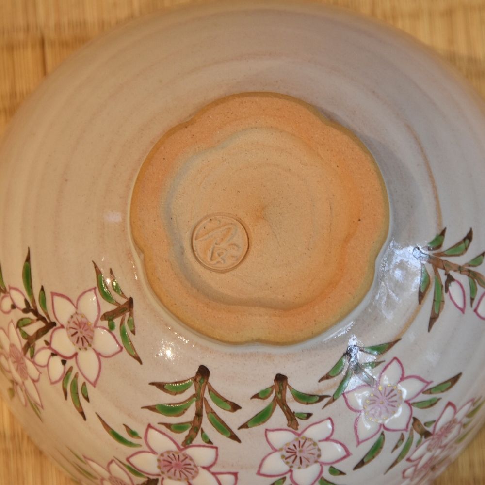 Close-up of the peach-blossom-shaped foot and impressed maker's mark on the underside of the Kyo Ware matcha bowl.
